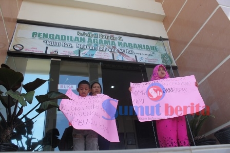 Kedua anak (memegang kertas karton) bersama ibu kandung mereka, Sarmila br Sembiring (tengah) saat melakukan aksi di Kantor Pengadilan Agama Kabanjahe, Kamis (17/3). SUMBER/pardi simalango
