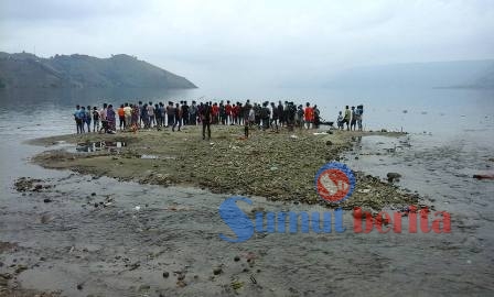 Kerumunan warga ditepi Danau Toba menyaksikan pencarian korban yang terseret arus sungai. SUMBER/Ist