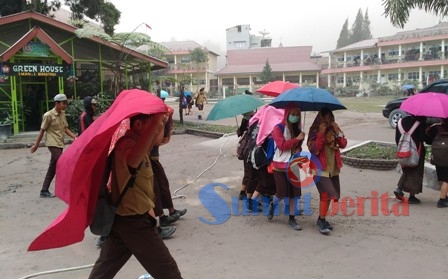 Sejumlah siswa SMA Negeri 1 Berastagi, mengenakan paying dan perlengkapan lainnya untuk berlindung dari guyuran debu vulkanik. SUMBER/pardi simalango